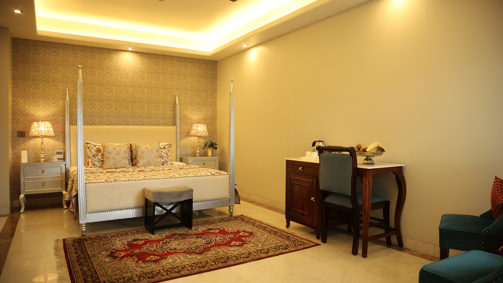 The Deluxe Heritage Suite in Jaipur at Dileep Kothi with a double bed and a work desk and chair.